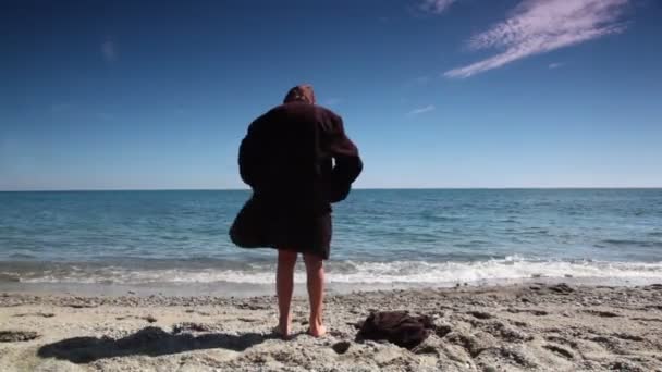 Chico en traje de hombre chaqueta de pie detrás de la cámara en la playa — Vídeos de Stock