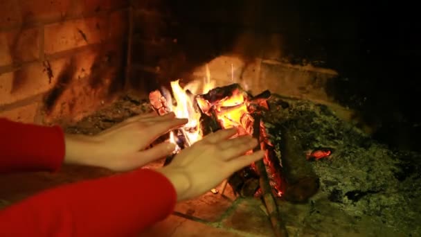 Mujer mantiene sus manos cerca del fuego de la chimenea — Vídeos de Stock