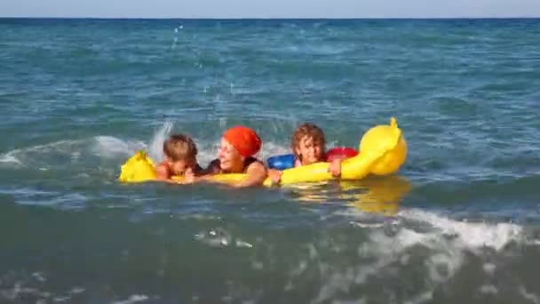 Мама з двома дітьми плаває в хвилястому морі — стокове відео
