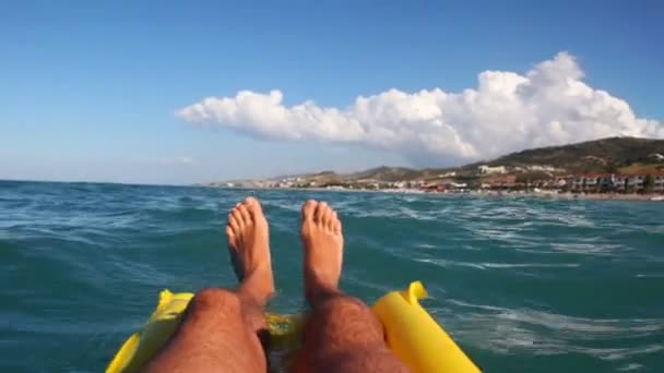 사람의 다리 매트리스와 바다 표면에 수영 — 비디오