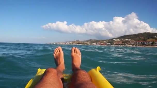 Legs of man swim on sea surface with mattress — Stock Video