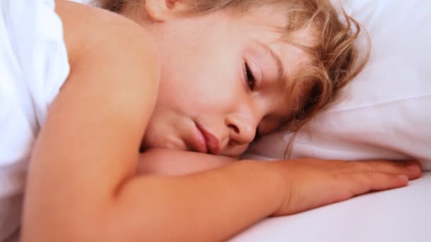 Küçük kız openes onu gözleri ve yastık üzerinde uyanık — Stok video