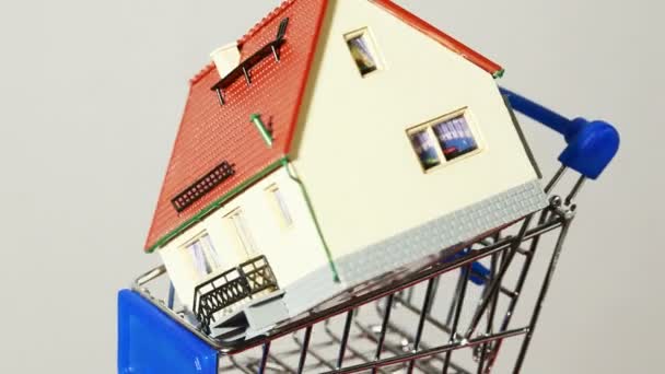 Modelo de casa dentro del pequeño carrito de compras girando en la plataforma — Vídeo de stock