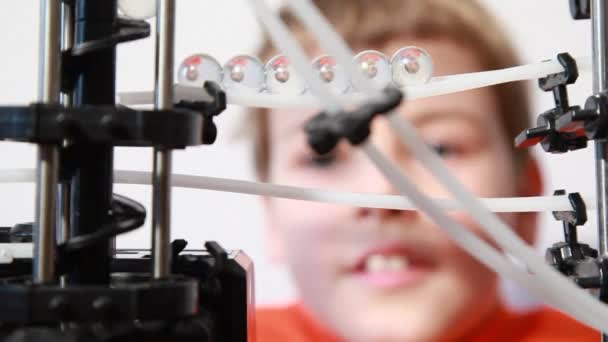 Boy looks at marbles inside run machine which reflect head — Stock Video