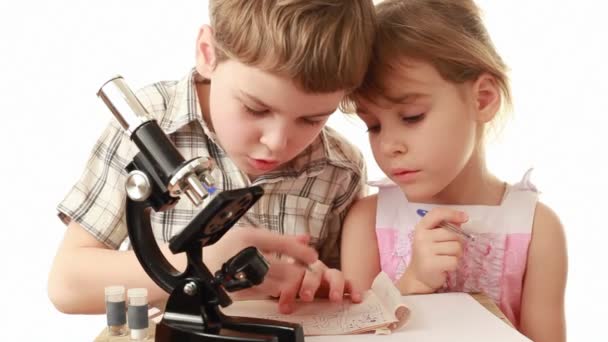 Boy teach little girl and writes something in notebook — Stock Video