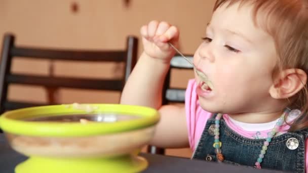 Baby flicka äter gröt och mammor arm torkar hennes mun — Stockvideo