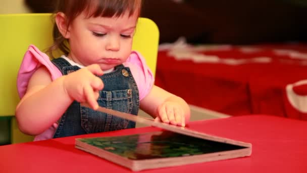 Bebê menina está sentado na cadeira e está abrindo o livro — Vídeo de Stock