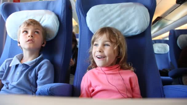 Bruder und Schwester sitzen auf Plätzen im Zug und hören Musik — Stockvideo