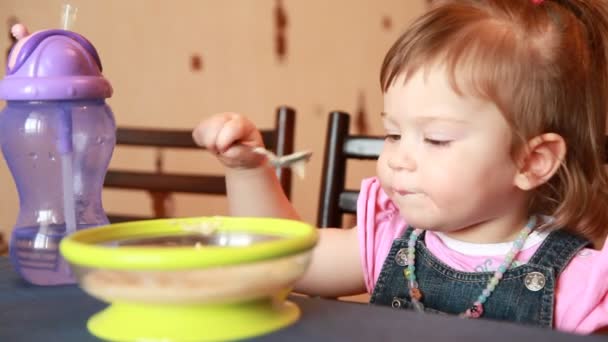 Bebé niña comer dos cucharadas de gachas — Vídeo de stock