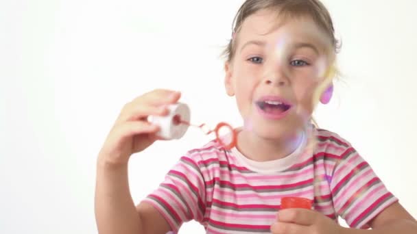 Девушка дует мыльные пузыри и пытается поймать их палкой — стоковое видео