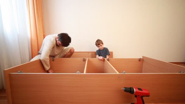Отец и сын строят деревянный шкаф дома — стоковое видео