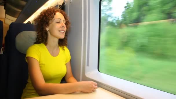 Woman sits and smiling in train near window during movement — Stock Video