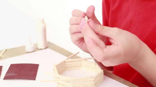 Boy apply glue on stick and attach it to wall of match house — Stock Video