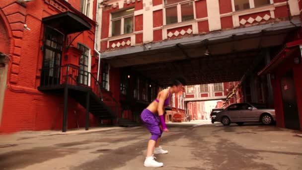 Danse féminine active sur la voie de la ville entre les maisons — Video