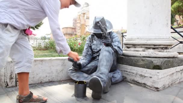 Busker earns living sitting on sidewalk, depicting stone statue cowboy, boy threw him coin — Stock Video