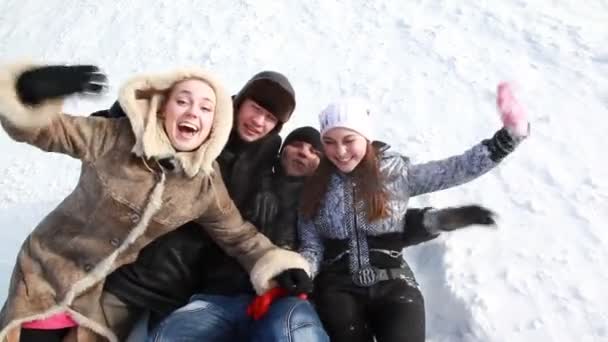 Молодые люди лежат на снегу и смеются . — стоковое видео