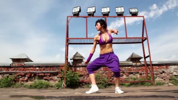 Woman performs modern dance, at background of small wall — Stock Video