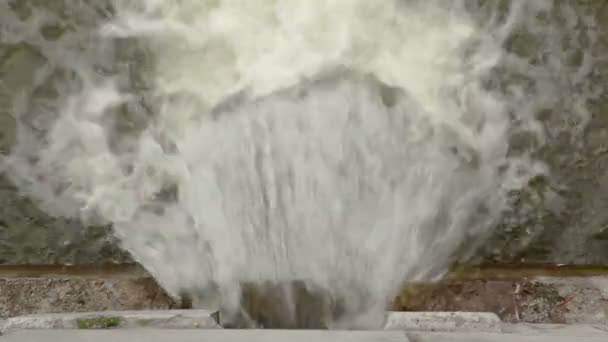 El flujo de agua está saliendo del agujero en la pared de piedra — Vídeos de Stock