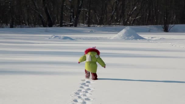 Flicka gå av djup snö till skog på bakgrunden — Stockvideo