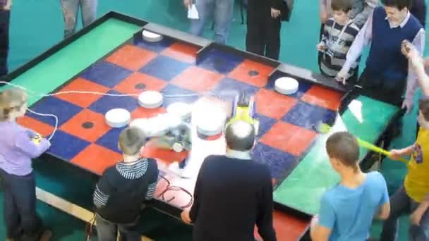 Роботы поднимают предметы на стол во время турнира по мини-роботам — стоковое видео