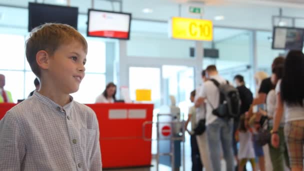 Chłopak mówi do kogoś w pobliżu kontroli paszportowej na lotnisku — Wideo stockowe