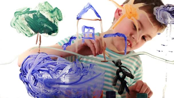 Boy draws picture of colored paint on transparent glass — Stock Video