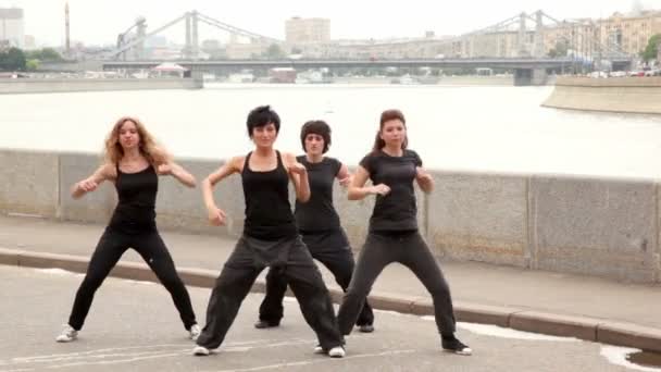 Cuatro chicas se paran una por una y comienzan a bailar en estilo moderno sincrónicamente en el muelle — Vídeos de Stock