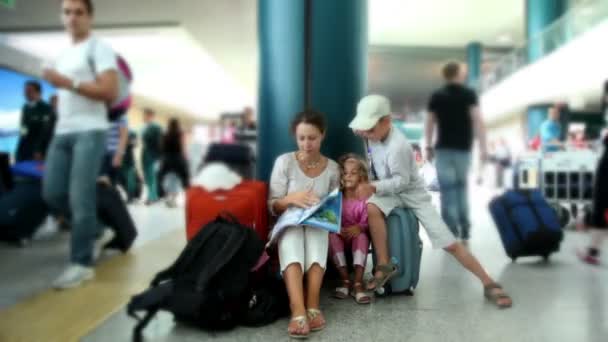 Mother and kids sit in airport and reading book — Stock Video