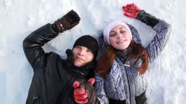 Couple are lying on the snow holding hands — Stock Video