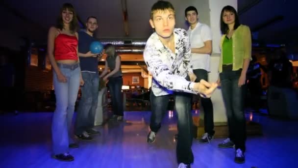 El hombre lanza la pelota y sus amigos se regocijan por el éxito en el club de bolos — Vídeo de stock