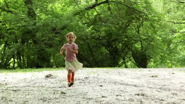 Girl runs closer across forest meadow all strewn fluff — Stock Video