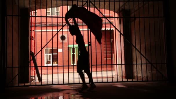 Mujer joven realiza danza moderna con tela cerca de puerta de celosía — Vídeos de Stock