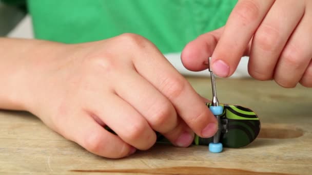 Boy kencangkan satu roda erat-erat untuk fingerskate menggunakan alat kecil — Stok Video