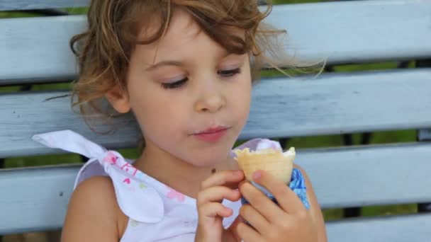 Niña comer helado y sentarse en el banco en el parque — Vídeos de Stock