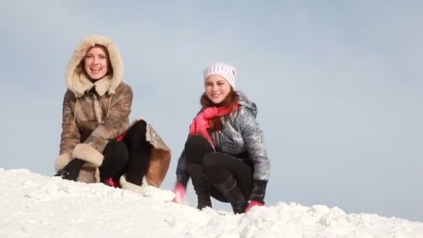 Die Frauen sitzen und werfen Schnee — Stockvideo