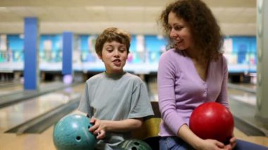 Anne ve oğlu bowling topları ellerinde tutmak ve parlak kulübünden