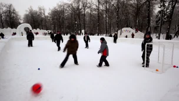 Дети играют в футбол в парке в зимний день, люди ходят вокруг, вид на угол — стоковое видео