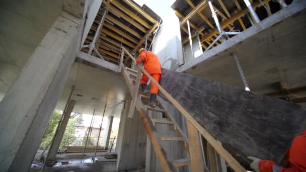 Робітники несуть величезну тарілку сходами до другого поверху — стокове відео