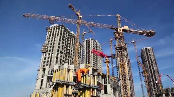 Bauarbeiter arbeitet vor dem Hintergrund der Hochhäuser auf der Baustelle — Stockvideo