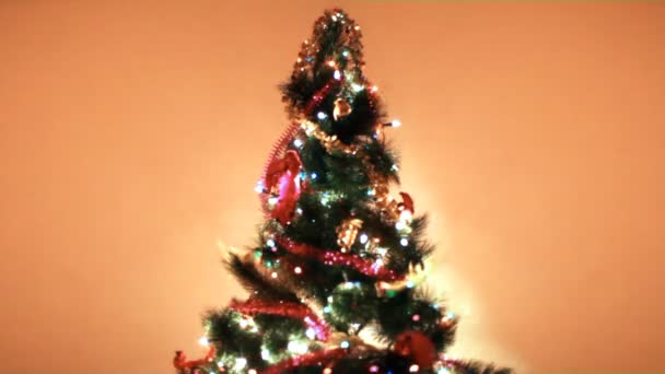 Χριστουγεννιάτικο δέντρο ανάβει πολύχρωμα φώτα σε φόντο τοίχο στο δωμάτιο — Αρχείο Βίντεο