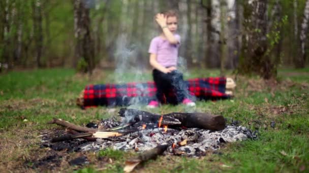 Kleines Mädchen sieht am Lagerfeuer zu, Junge kommt und sitzt in der Nähe — Stockvideo