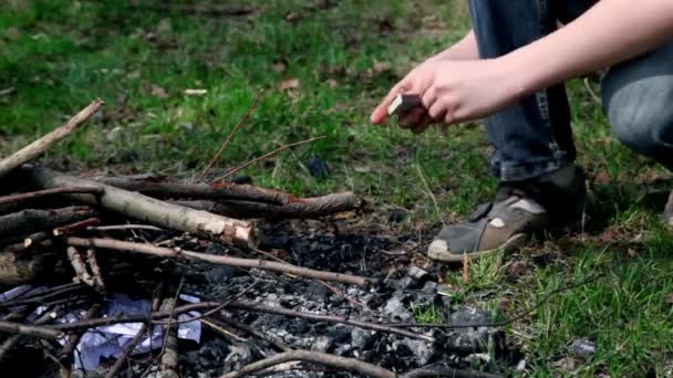 Niño enciende hoguera con fósforo, solo las piernas son visibles — Vídeos de Stock