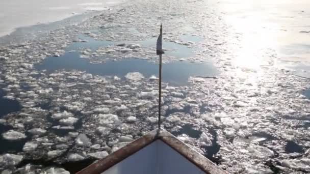Vlajku letět v přídi lodi, která pluje po řece s krakované ledu — Stock video