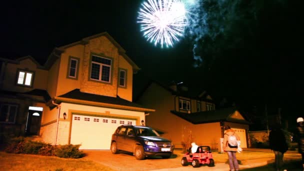 Poche persone guardano fuochi d'artificio al cielo scuro sopra casa nel villaggio cottage — Video Stock