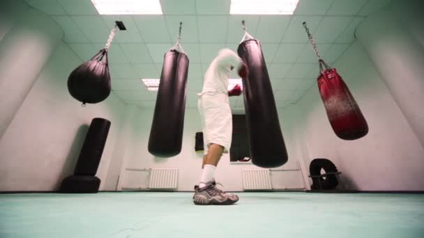 Hombre con guantes golpea saco de boxeo grande en el gimnasio de boxeo grande — Vídeo de stock