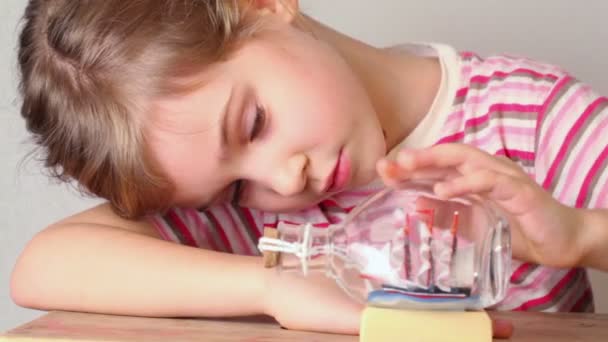 Fille regarde le modèle de haut en verre bouteille stand sur la table — Video