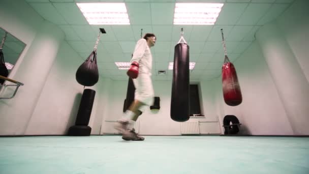 Homem de luvas corre e socos no ar no ginásio de boxe — Vídeo de Stock