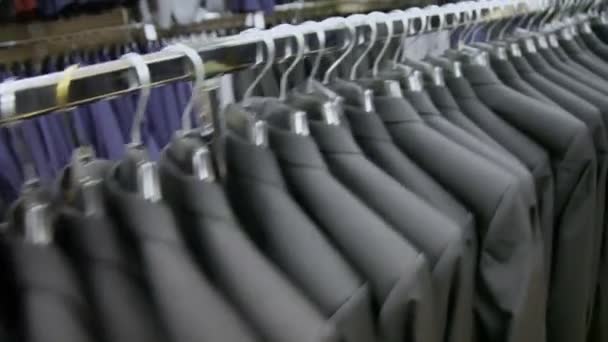 Vista de algunas chaquetas idénticas en perchas en la tienda — Vídeo de stock