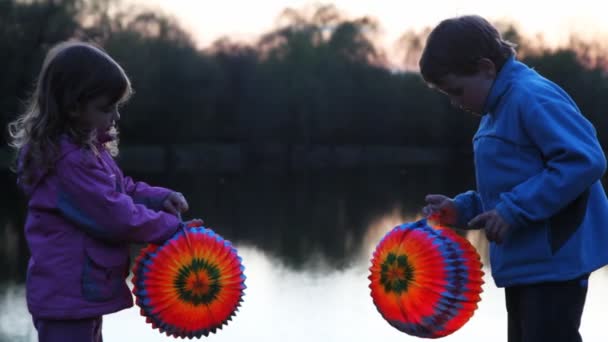 Boy and girl hold colorful ball from paper at night — Stock Video