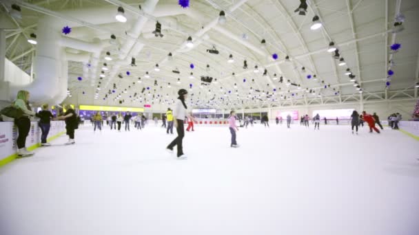 Viele Menschen Schlittschuhlaufen auf großer Indoor-Eisbahn in Einkaufszentrum — Stockvideo